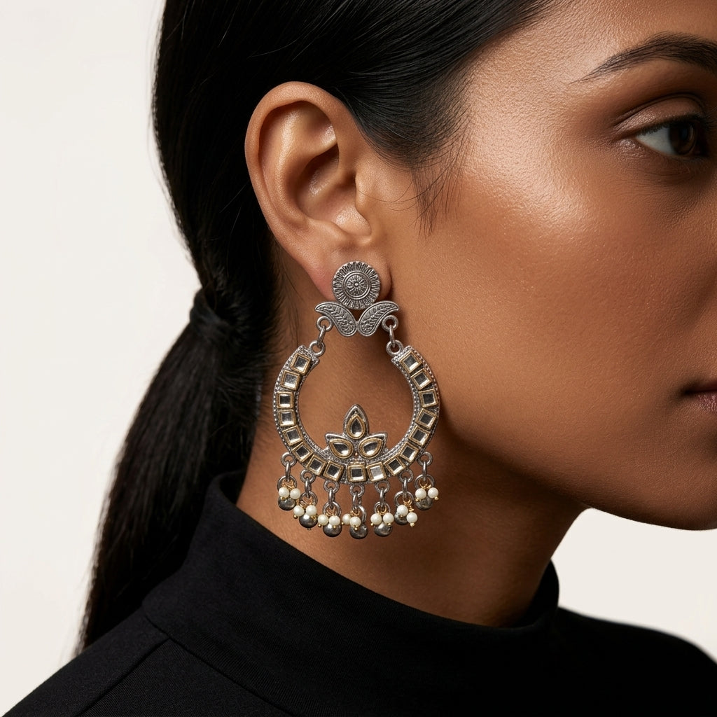 Close-up side view of ornate chandelier earring worn beside a black high-neck top