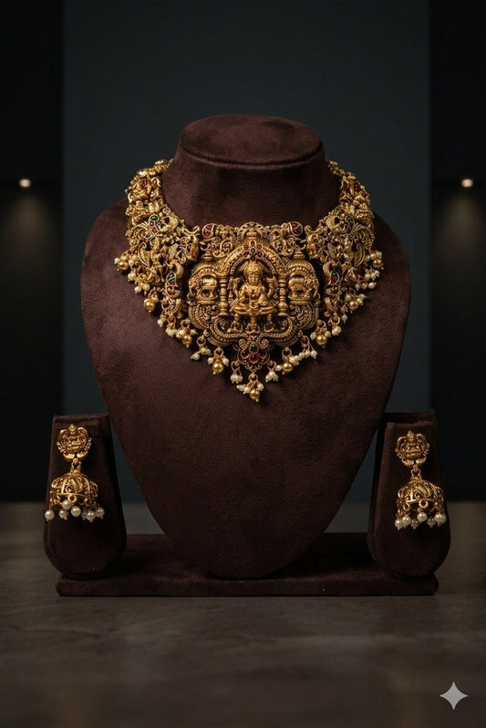 Front view of ornate necklace on brown bust, with matching-looking earrings displayed on either side