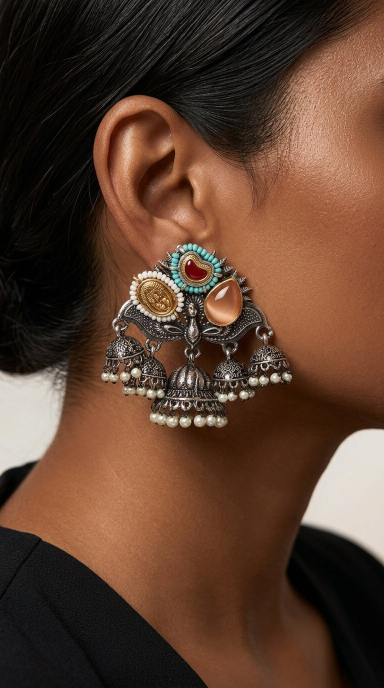 Close-up of ornate dangling earring worn against dark hair, showing layered drops and white bead fringe