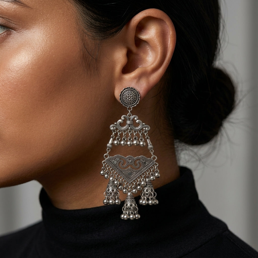 Long ornate chandelier earring worn against dark hair and a black high-neck top