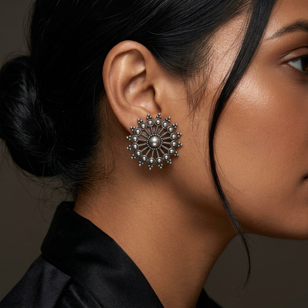 Close-up side view of a round sunburst earring worn against the ear