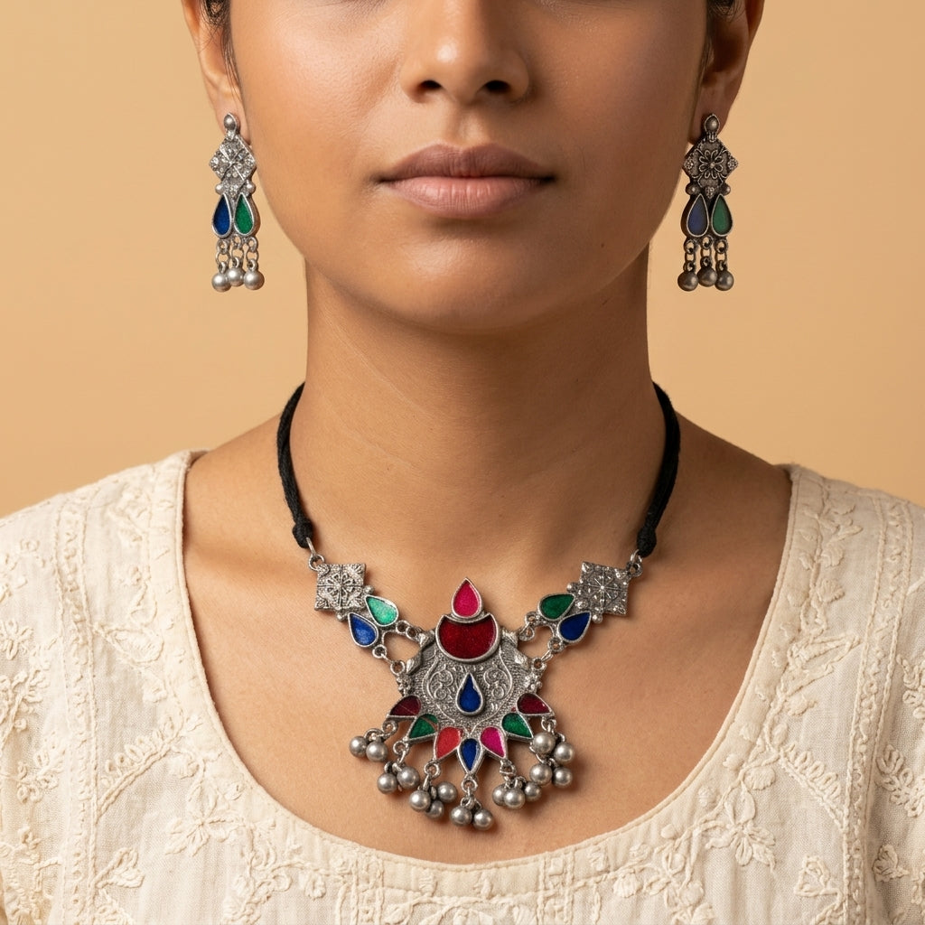 Front-facing close-up of worn drop earrings with blue, green, and dangling round details