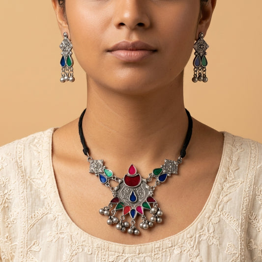 Front-facing close-up of worn drop earrings with blue, green, and dangling round details
